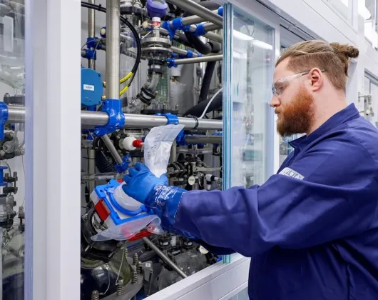Man in a blue work uniform in a pharmaceutical drug substance manufacturing facility