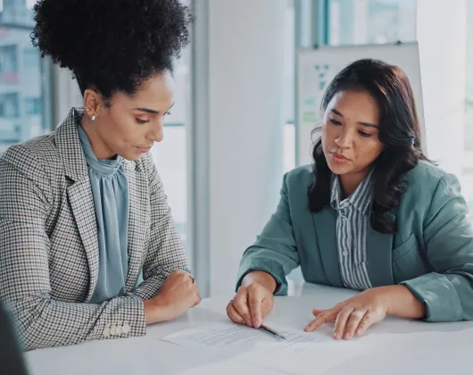 Two women speaking and reviewing a report